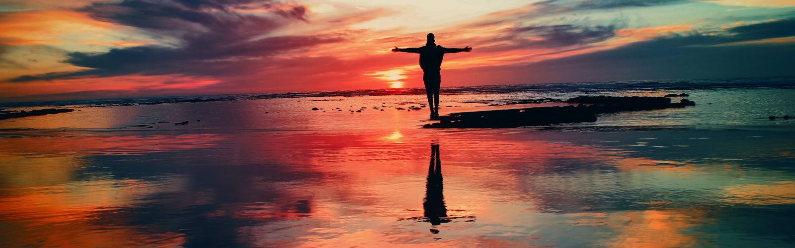 Silhouette Of Person Standing On Rock Surrounded By Body Of Water, from unsplash