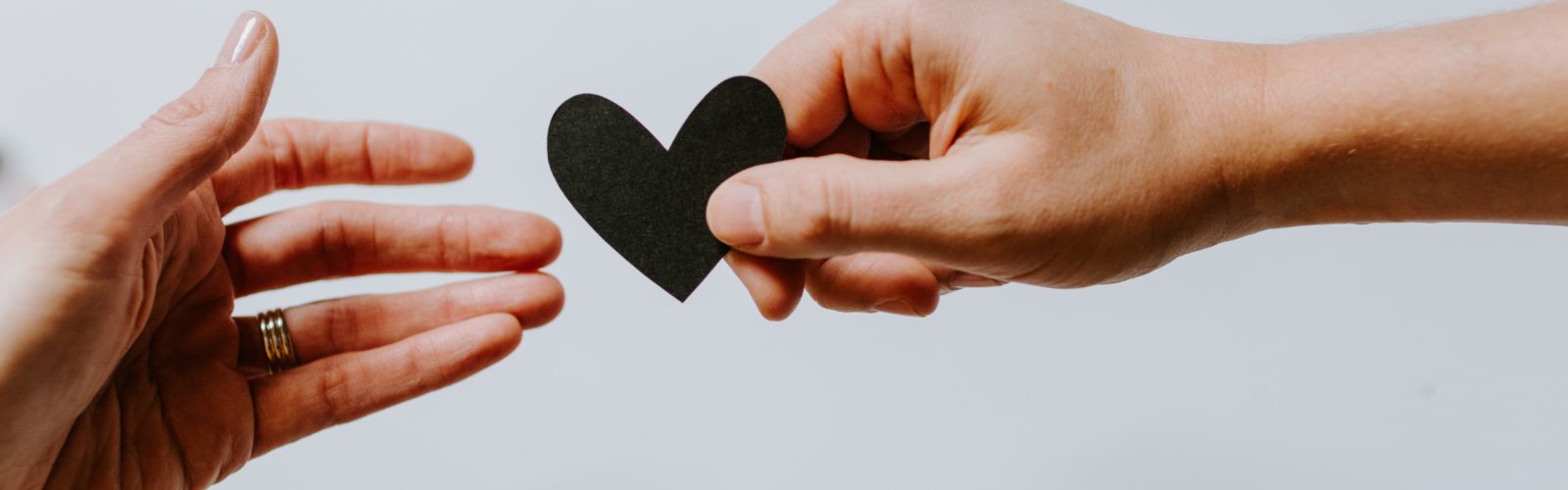 Two hands, one offering a paper heart to the other. Image by Kelly Sikkema, from Unsplash